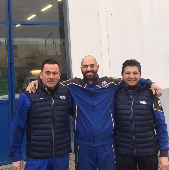 Tre membri del team di Nuova Omer in abbigliamento da officina